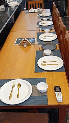 a long wooden table with white plates and silverware at Geetanjali Palace Hotel & Restaurant in Rudraprayāg