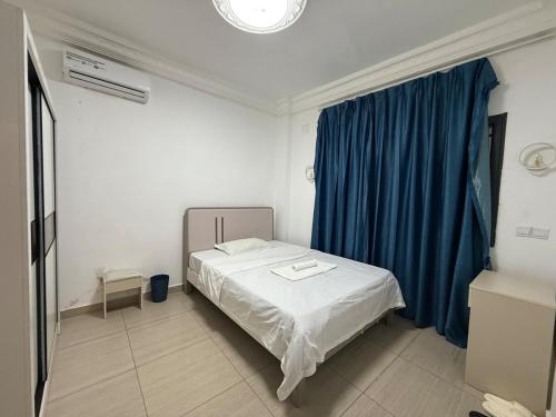 a bedroom with a bed and a blue curtain at Easy home in Brazzaville