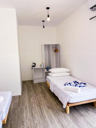 two beds in a room with white walls and wooden floors at Shadow Isles Himandhoo in Himandhoo 
