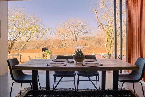 a wooden table with chairs and a potted plant on a patio at Amani Luxury Villa Marloth Park in Marloth Park