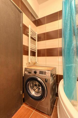 a washing machine in a bathroom next to a tub at Apartament 3 camere Militari Residence in Dudu