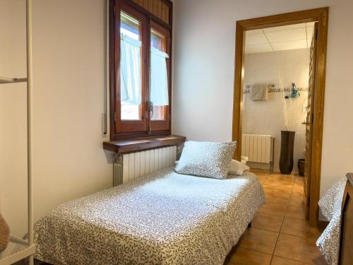 a small bedroom with a bed and a window at Apartaments Cel i Fusta in Camprodon