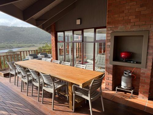 a wooden table and chairs on a deck with a television at Wilderness deckhouse. views!/sun/sea/river/kayaks in Wilderness