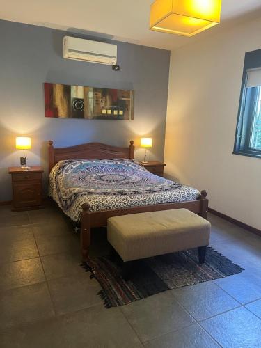 a bedroom with a bed and a bench and two lamps at Alma Quinta Maschwitz muy cerca de Temaiken in Maquinista Savio