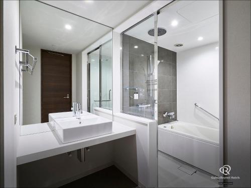 a white bathroom with a sink and a bath tub at Daiwa Roynet Hotel Fukuyama Ekimae in Fukuyama