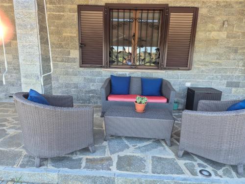Un patio con sillas de mimbre y un sofá con almohadas azules. en Il Quadrifoglio, en Pavarolo