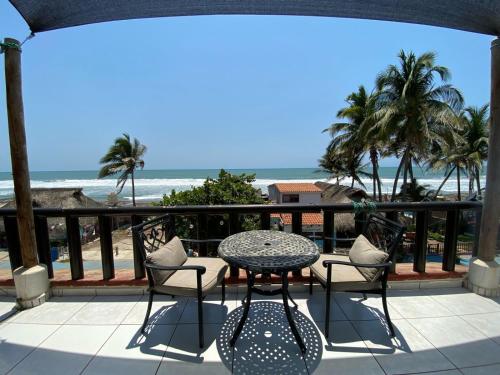 a table and chairs on a balcony with the beach at La Orquidea Bonfil in Acapulco