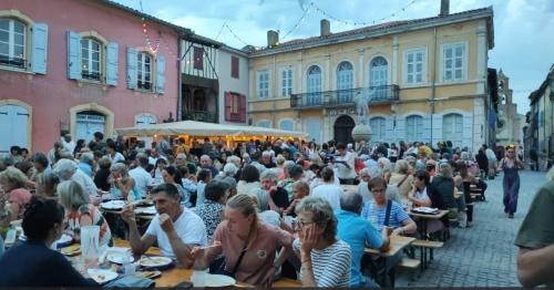 a crowd of people sitting at tables in a courtyard at 85 m2 de plain-pied dans maison confortable avec vue sur la vallée et les Pyrénées ariégeoises, grande terrasse avec barbecue et parking gratuit in Castéras