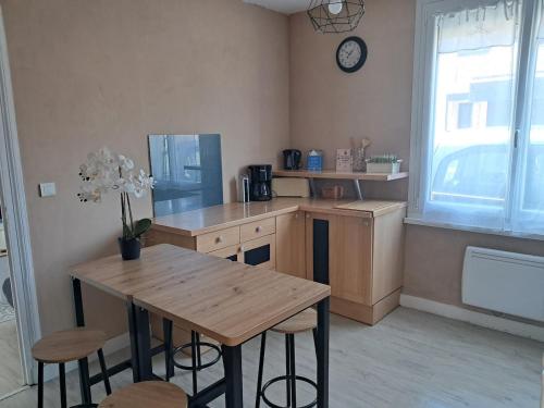 a kitchen with a wooden table and chairs and a clock at Maison à 50m de la plage in Gâvres