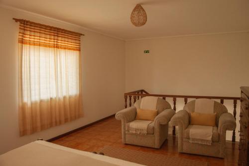 two chairs in a living room with a window at Swara Slow Living Home in Aveiro