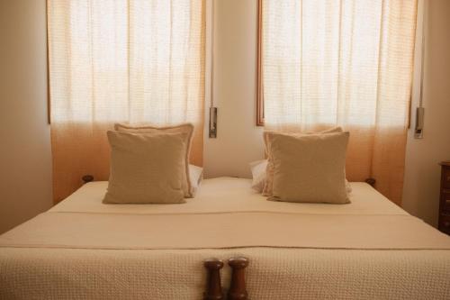 a bed with white sheets and pillows in a bedroom at Swara Slow Living Home in Aveiro