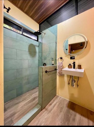 a bathroom with a shower and a sink and a mirror at Jungle House with Private Jacuzzi in Uvita