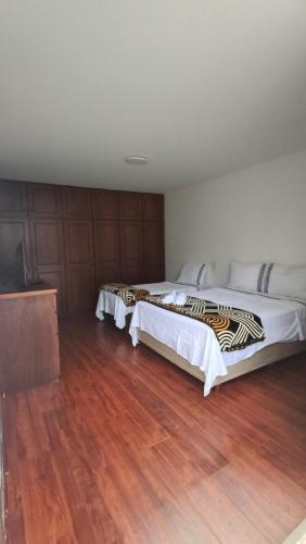 two beds in a room with wooden floors at Hospedagem Jardim Social,Quartos Econômicos e Suítes, Estacionamento Grátis in Curitiba