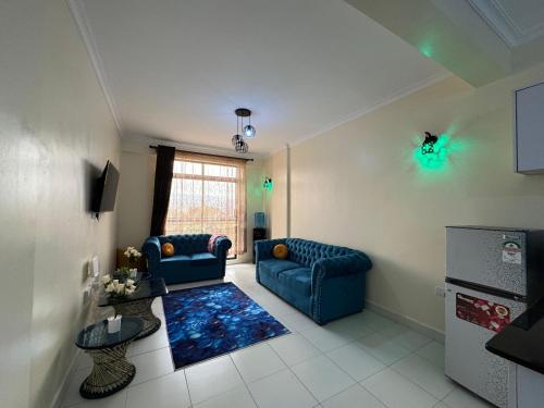 a living room with two blue couches and a kitchen at Anny's bnb in Ngong