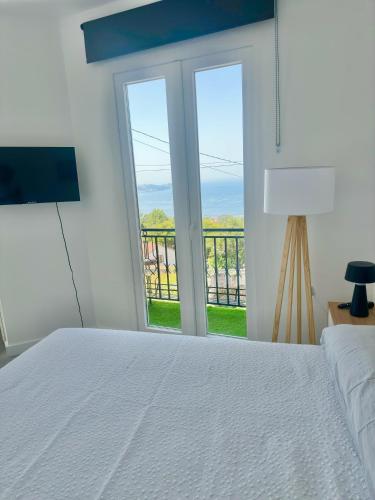 a bedroom with a white bed and a large window at Apartamentos Isla del Santo in Marín
