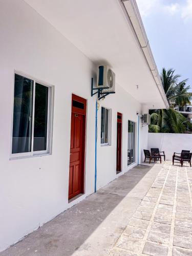 a white building with a red door and a patio at Shadow Isles Himandhoo in Himandhoo 