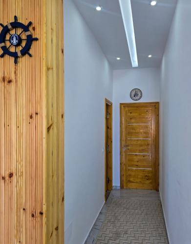 a hallway with a wooden door and a clock on the wall at La Marine Tabarka in Tabarka