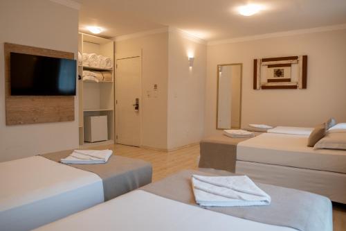 a room with three beds and a flat screen tv at Lagoa Parque Hotel in Lagoa Vermelha