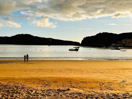 two people standing on a beach with a boat in the water at One Bedroom Chalet with private bathroom and kitchen in Alcobaça