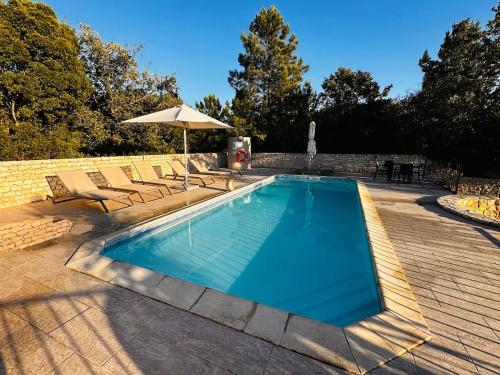 a swimming pool with chairs and an umbrella at One Bedroom Chalet with private bathroom and kitchen in Alcobaça