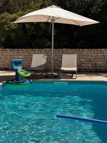 a swimming pool with an umbrella and two chairs and aogieoganearch at One Bedroom Chalet with private bathroom and kitchen in Alcobaça