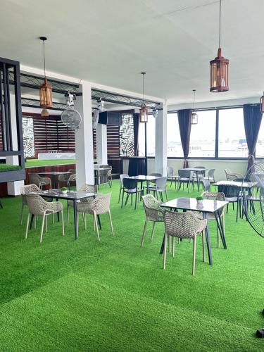 a room with tables and chairs and green grass at Royal Breeze Paramaribo in Paramaribo
