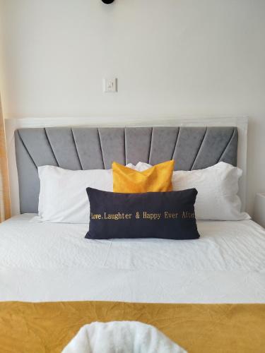 a bed with a gray headboard with two pillows at Kiambu cozy studio in Kiambu