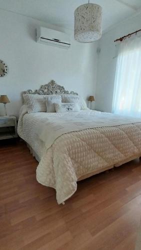 a bedroom with a large white bed with a wooden floor at Arena de Mar depto A in Mar de las Pampas