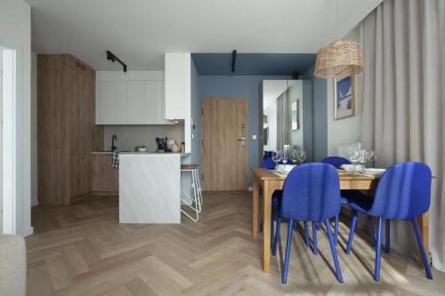 a kitchen and dining room with a table and blue chairs at Pino 46 Sobieszewo Gdańsk in Gdańsk