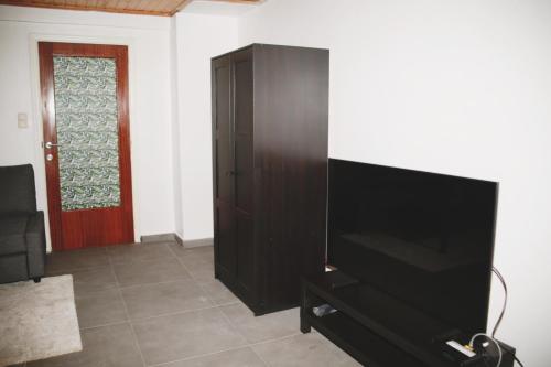 a living room with a flat screen tv and a cabinet at Tumaini House in Antwerp