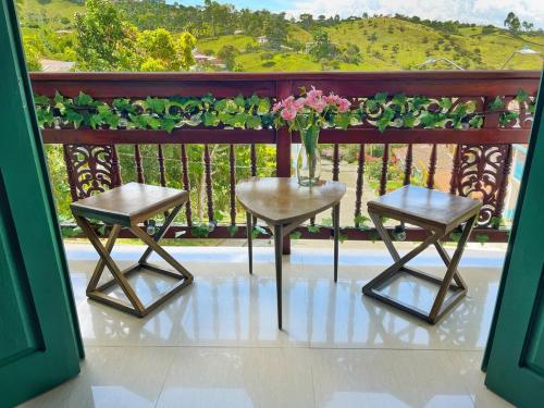 two chairs and a vase of flowers on a balcony at Blomst Casa Hostal in Jericó
