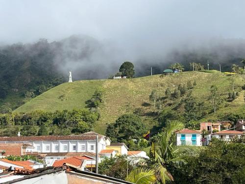 a green hill with a house on top of it at Blomst Casa Hostal in Jericó