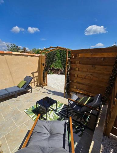 a patio with chairs and a wooden fence at Mini Loft à la campagne La BA-LINE in Entrecasteaux