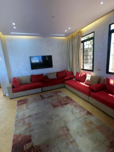 a living room with a red couch and a flat screen tv at villa vue sur mer avec piscine in Al Houara