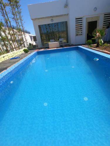 a large blue swimming pool in front of a building at villa vue sur mer avec piscine in Al Houara