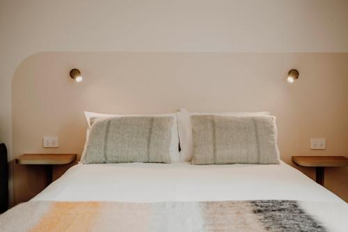 a bedroom with a white bed with two pillows at The Cudgee at Mudgee in Mudgee