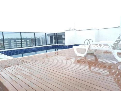 a wooden deck with a bench on top of a building at Apartamento Ponta Verde in Maceió