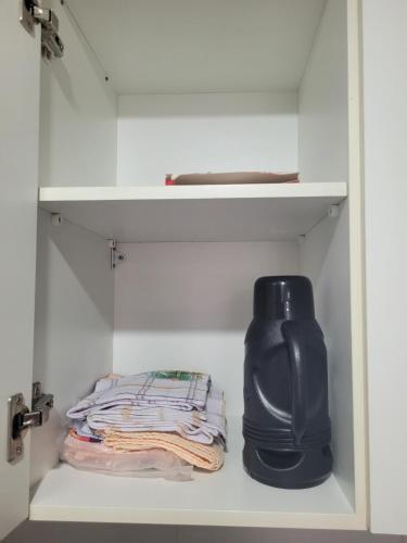 a white closet with a black vase sitting on a shelf at Apartamento Ponta Verde in Maceió