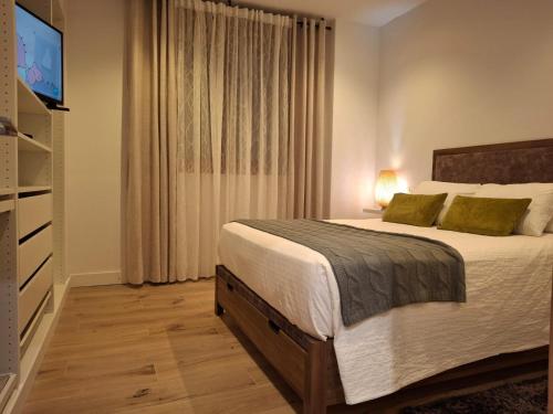 Un dormitorio con una cama grande y un televisor. en La casa de Teresa, en Santiago de Compostela