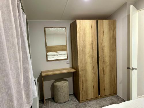 a bedroom with a wooden cabinet and a mirror at Blosseys Beach House in South Hayling
