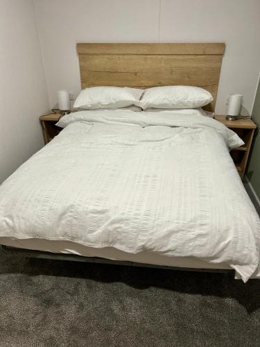 a large white bed with white sheets and pillows at Blosseys Beach House in South Hayling