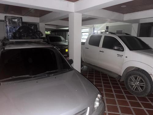 a white truck parked in a garage with a car at Hotel San Francisco Real in Villagarzón