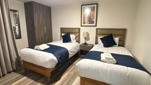 a bedroom with two beds with blue and white sheets at Pascana Hotel in Chivay