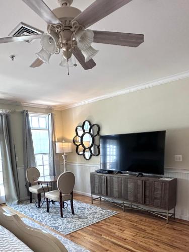 a living room with a ceiling fan and a flat screen tv at Inn on Main Hotel in Manasquan