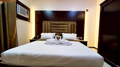 a bedroom with a large white bed with towels on it at فندق سمو العرب 