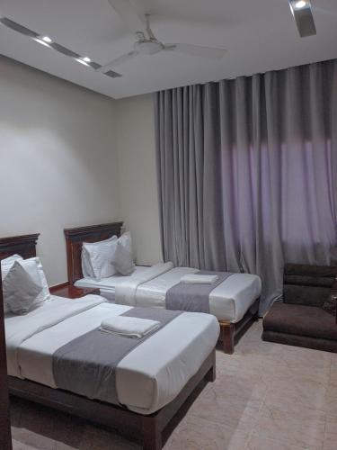 a hotel room with two beds and a chair at فندق سماء الإمارات in Khawr Maksar