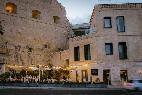 a building with a restaurant in front of a castle at Cugo Gran Macina Malta in Senglea