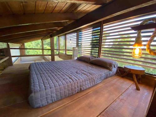 a bedroom with a bed in a room with windows at Chalé na Cachoeira dos Machados II - Bueno Brandão in Bueno Brandão