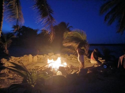 a person standing around a fire on the beach at night at Hotel xahuayxol in Mahahual