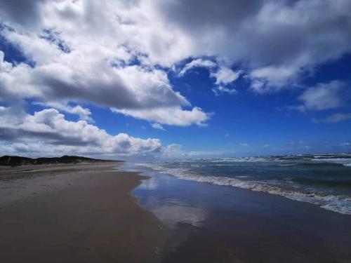 a beach with a cloudy sky and the ocean at 6 person holiday home in Brovst-By Traum in Brovst